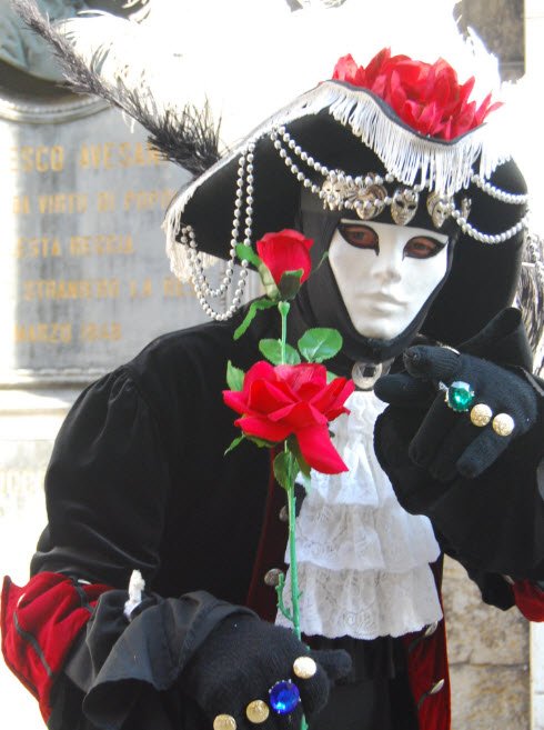 Plongez dans l'atmosphère envoûtante et intemporelle du Carnaval de Venise par l'artiste Carmen Cortizo.
L'image met en scène une figure énigmatique arborant le célèbre masque blanc vénitien, encadré d'un somptueux tricorne noir orné de perles fines, de miniatures et de plumes vaporeuses. Le contraste saisissant entre la profondeur du velours noir, la délicatesse du jabot en dentelle blanche et l'éclat flamboyant de la rose rouge confère à ce cliché une puissante dimension dramatique et baroque.
Avec son regard perçant dissimulé et son geste théâtral orné de bagues précieuses, ce portrait incarne toute la magie, le mystère et la tradition du grand carnaval italien. Une œuvre photographique idéale pour les amateurs d'art visuel, d'ambiances vénitiennes et d'esthétique baroque contemporaine.

Carnaval de Venise - Photographie Carmen Cortiso — Carmen Cortizo