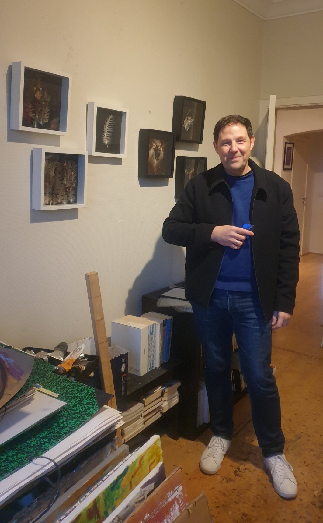 Le plasticien Eric Schmickrath photographié tout sourire lors de l'accrochage de ses œuvres à l'espace SELOSSE ART (22 avenue Armand Huysmans). Pour le Parcours d'Artistes d'Ixelles 2026, cet artiste d'origine arlonaise installé à Bruxelles présente ses collages uniques mêlant plumes, papier et coquilles d'œuf. Ses figures oniriques et mélancoliques sont à découvrir au sein d'une exposition collective réunissant six artistes belges. 

Liens :
Plongez dans l'univers onirique d'Eric Schmickrath, fait d'assemblages poétiques de plumes et de papier, à l'occasion du Parcours d'Artistes d'Ixelles 2026 ! Ses œuvres sont présentées lors d'une exposition collective de six artistes belges chez SELOSSE ART (22 avenue Armand Huysmans).
🕒 Horaires d'ouverture : le vendredi 6 novembre (18h-22h), le samedi 7 novembre (12h-20h) et le dimanche 8 novembre (10h-17h).
Pour en savoir plus sur l'artiste, visitez son site web (https://ericleyders.wixsite.com/website) ou consultez son profil sur Dropmuse : https://dropmuse.art/artiste/eric-schmickrath-plasticien-bruxelles.
Retrouvez toutes les infos de cette exposition collective sur la fiche de l'événement Dropmuse : https://dropmuse.art/evenement/exposition-collective-de-6-artistes-belges-a-ixelles-bruxelles-parcours-dartistes-2026-selosse-art-2

Photographie — Exposition collective de 6 artistes belges à Ixelles, Bruxelles — Parcours d'Artistes 2026, SELOSSE ART