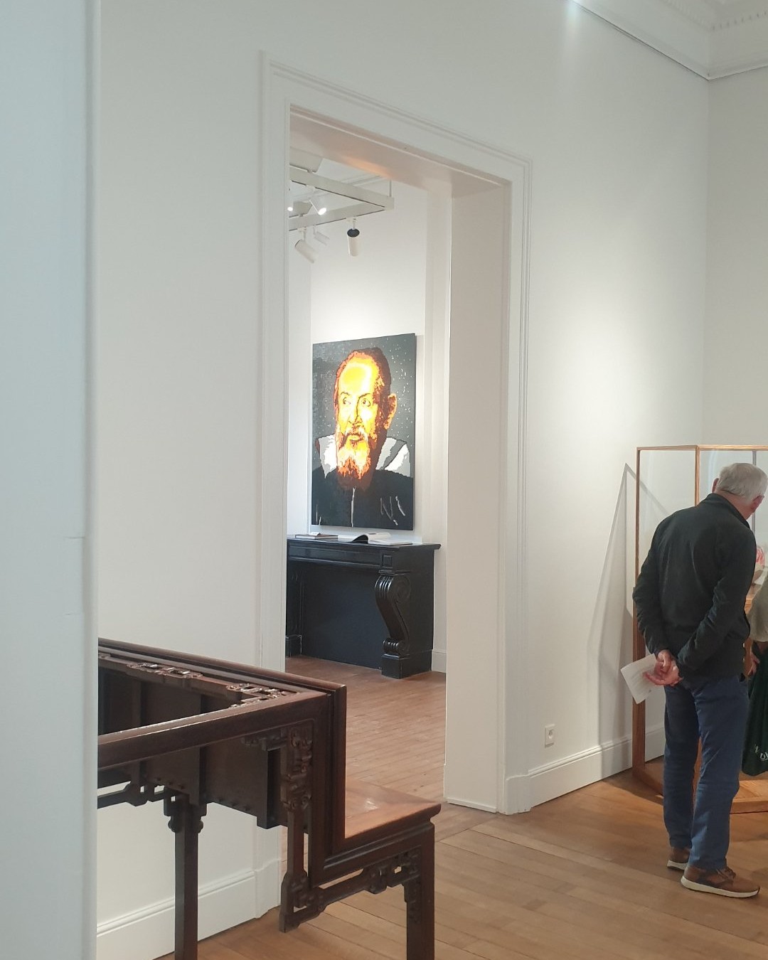 Vue architecturale cadrée depuis l'escalier de la Patrick Derom Gallery, dévoilant un visiteur en contemplation devant un portrait réinterprété au-dessus d'une cheminée d'époque. Ce contraste entre la sobriété bourgeoise du lieu et l’audace formelle d’Ai Weiwei crée une tension spatiale remarquable. Une atmosphère captée lors de la visite commune des artistes bruxellois Jérôme Selosse ( https://dropmuse.art/artiste/jerome-selosse-artiste-numerique-dessinateur-bruxelles ) et Txema Muñoz ( https://dropmuse.art/artiste/txema-munoz / https://texemamunoz.art ), soulignant la force scénographique de l'événement. Pour explorer d'autres chroniques d'expositions et galeries bruxelloises, rendez-vous sur https://www.dropmuse.art

Photographie — Exposition Ai Weiwei - 'The Art of Defiance' - Patrick Derom Gallery Bruxelles