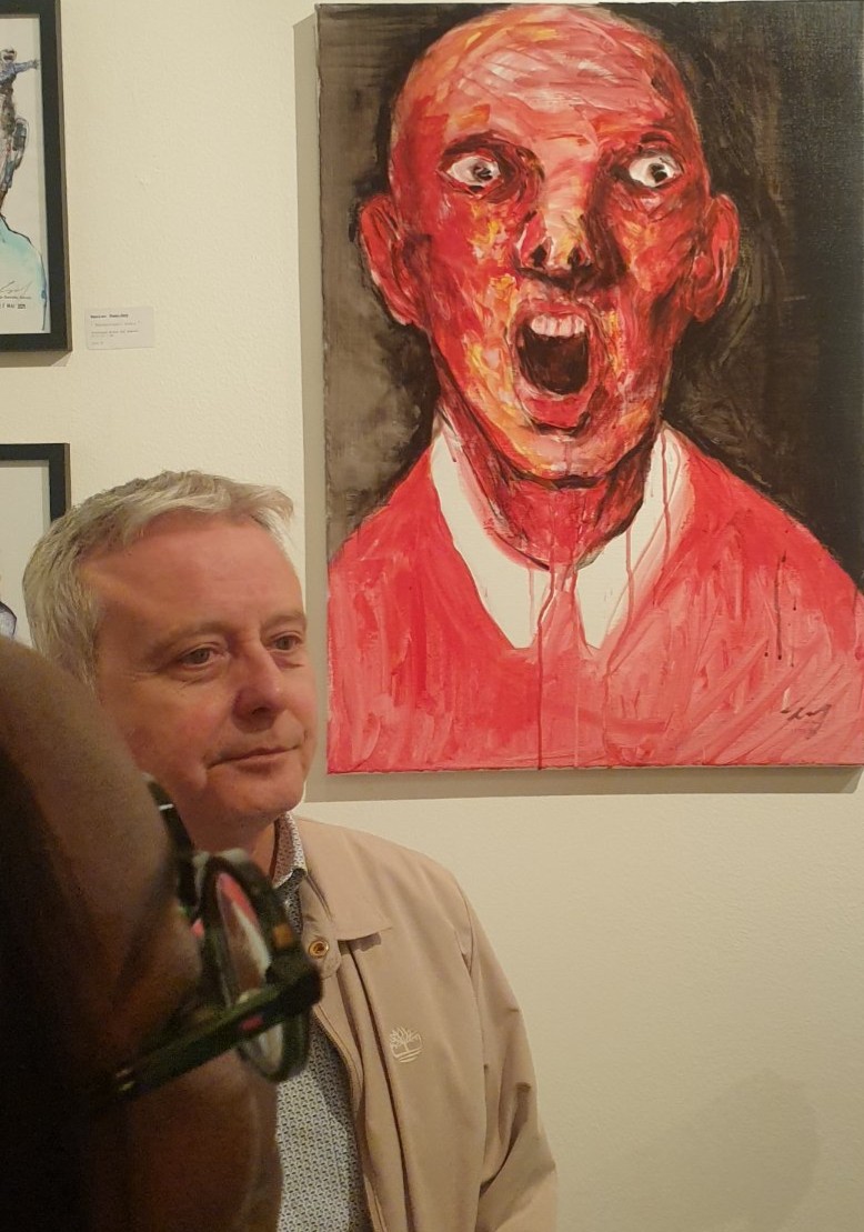 Un visiteur face à « The Shadow of the Leader », acrylique sur toile de Renier Semidey, au vernissage de « The Working Dead ».

Le contraste fait sourire : un visage calme au premier plan et, derrière, la toile qui hurle. Rouge vif, yeux exorbités, bouche béante, coulures de peinture sur le col blanc : Renier Semidey peint l'employé au bord de la rupture. Le genre de face-à-face que l'exposition provoque à chaque mur.

« The Working Dead » de Renier Semidey, jusqu'au 15 novembre 2026 chez Zaza from Brussels, rue Blaes 122, 1000 Bruxelles (Marolles). Le mercredi de 11h à 18h, du jeudi au dimanche de 11h à 19h. Entrée libre.

Voir les liens utiles en bas de la description.

🔗 Pour aller plus loin et soutenir l'art local :
L'exposition « The Working Dead » de Renier Semidey : https://dropmuse.art/evenement/the-working-dead-renier-semidey-zazafrombrussels-bruxelles-a9c827
Renier Semidey sur Instagram : https://www.instagram.com/renier_del_mediodia/
La fiche acteur culturel de Zaza from Brussels : https://dropmuse.art/acteur-culturel/zazafrombrussels
Le site de la galerie : https://zazafrombrussels.com/
Suivre la galerie sur Instagram : https://www.instagram.com/zazafrombrussels/
La galerie sur Facebook : https://www.facebook.com/GalerieZazafromBrussels/
Retrouvez toute l'actualité culturelle sur DROPMUSE : https://dropmuse.art/