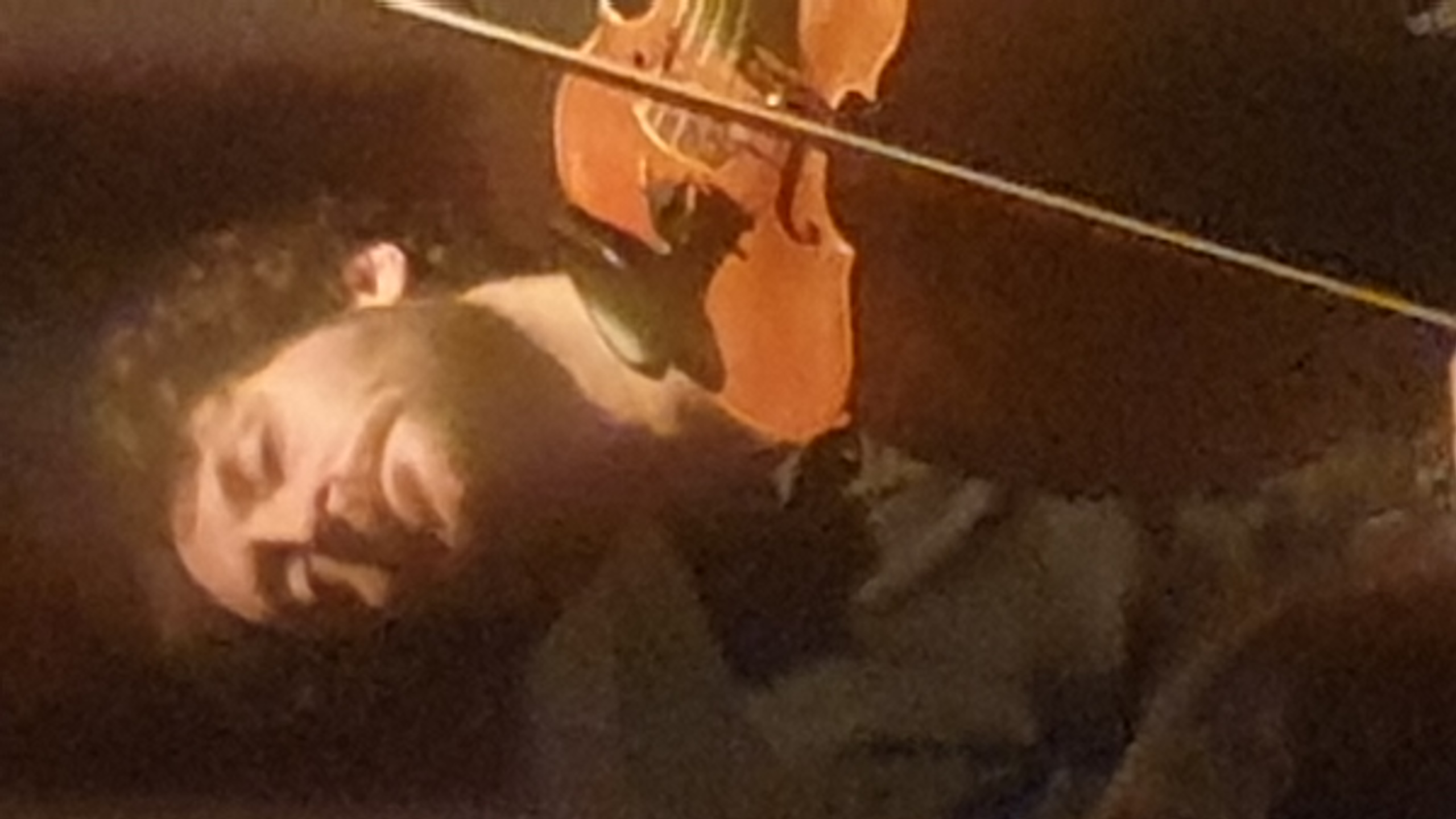Prestation violoniste lors d'un concert à Bruxelles, éclairage dramatique doré sur fond sombre. Spectacle - Concert à Art base. Salle de spectacle bruxelloise