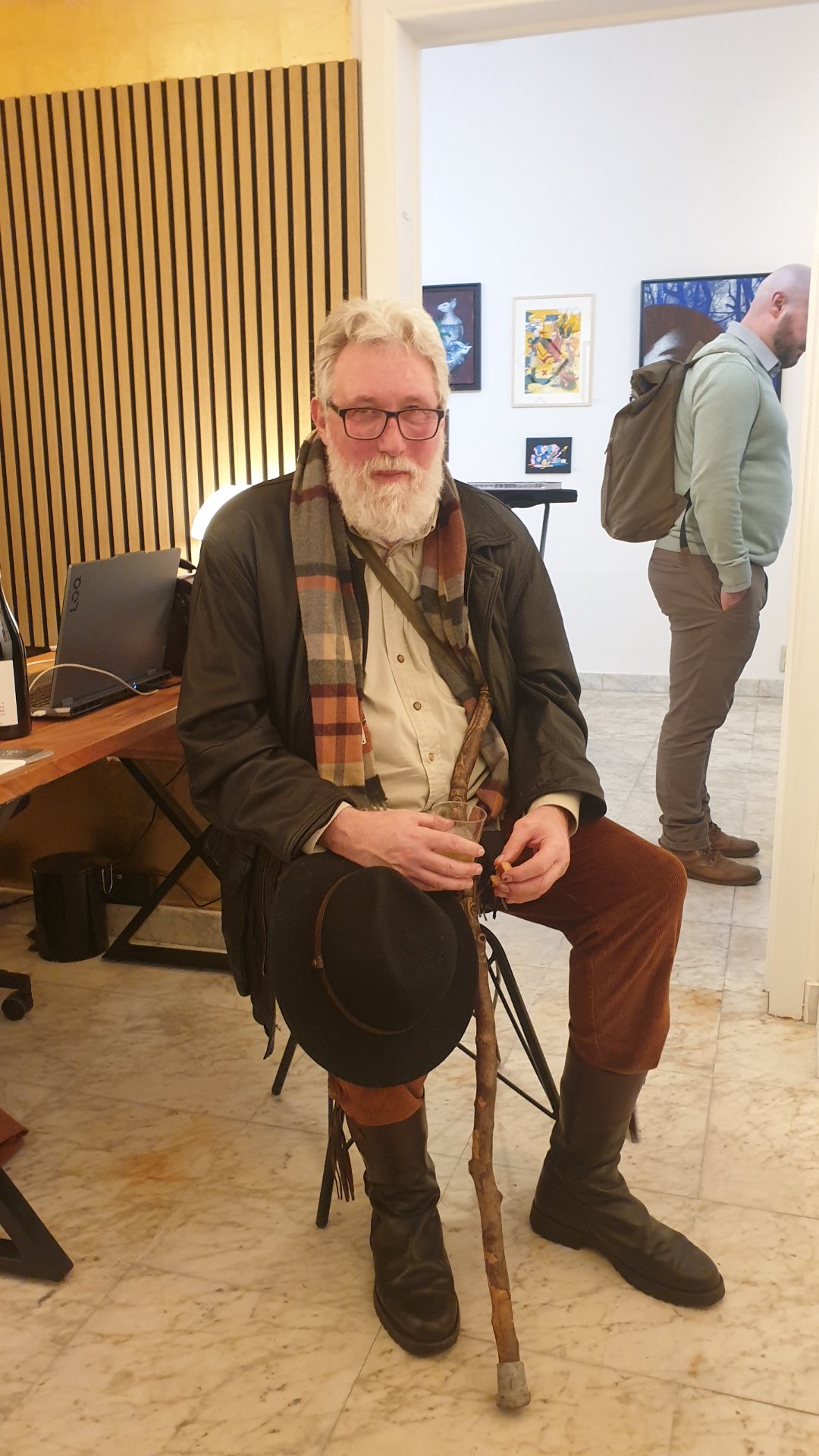 Le peintre Boris Mestchersky, chapeau sur les genoux et bâton de marche à la main, au vernissage de Renier Semidey chez Zaza from Brussels.

Barbe blanche, écharpe à carreaux, bottes de cuir : Boris Mestchersky a l'allure d'un voyageur. Né à Liège en 1963, formé à Saint-Luc puis à la gravure à l'Académie des Beaux-Arts, il vit et travaille à Huy. Sa peinture, centrée sur la couleur et la lumière, explore une dimension spirituelle nourrie de la Bible, de la musique et de la poésie.

« The Working Dead » de Renier Semidey, jusqu'au 15 novembre 2026 chez Zaza from Brussels, rue Blaes 122, 1000 Bruxelles (Marolles). Le mercredi de 11h à 18h, du jeudi au dimanche de 11h à 19h. Entrée libre.

Voir les liens utiles en bas de la description.

🔗 Pour aller plus loin et soutenir l'art local :
Le peintre Boris Mestchersky sur DROPMUSE : https://dropmuse.art/artiste/boris-mestchersky-peintre-plasticien-huy
L'exposition « The Working Dead » de Renier Semidey : https://dropmuse.art/evenement/the-working-dead-renier-semidey-zazafrombrussels-bruxelles-a9c827
La fiche acteur culturel de Zaza from Brussels : https://dropmuse.art/acteur-culturel/zazafrombrussels
Le site de la galerie : https://zazafrombrussels.com/
Suivre la galerie sur Instagram : https://www.instagram.com/zazafrombrussels/
La galerie sur Facebook : https://www.facebook.com/GalerieZazafromBrussels/
Retrouvez toute l'actualité culturelle sur DROPMUSE : https://dropmuse.art/