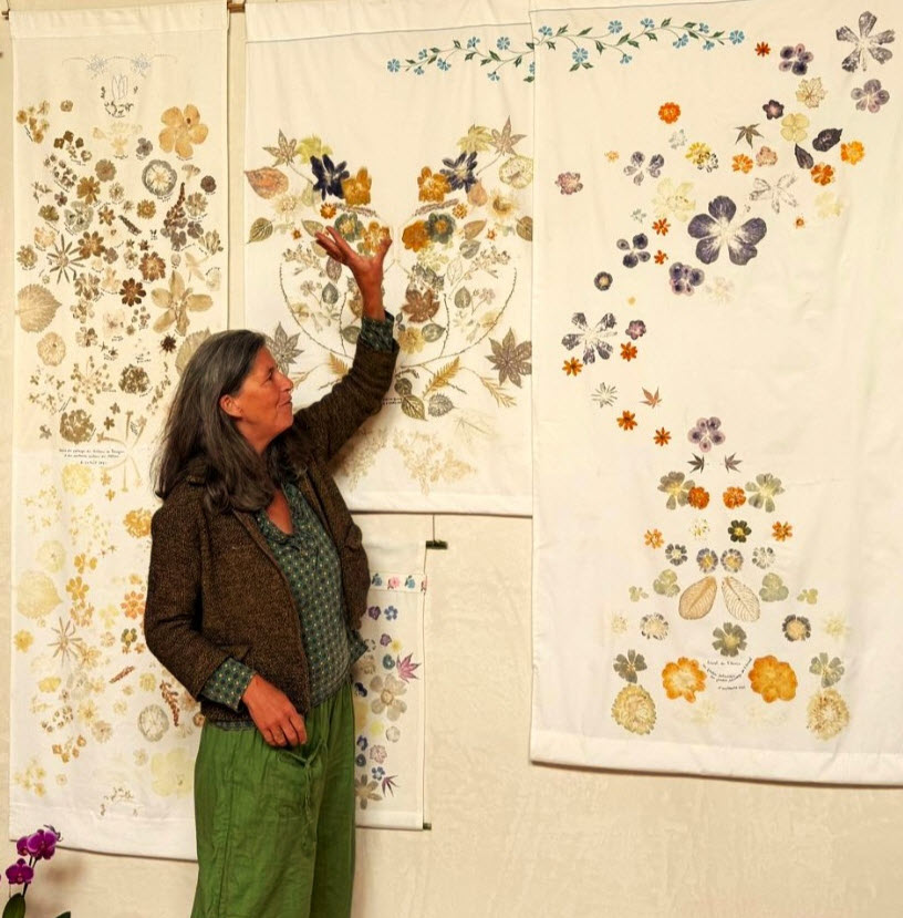 Sandrine de Borman devant une installation murale composée de centaines de fleurs séchées et pressées en teintes ocre, orange, pourpre et bleu, arrangées en motifs organiques sur papier blanc. Exposition florale de Sandrine de Borman


🌐 Site officiel (Ars Herbarium) : 
https://www.arsherbarium.com
