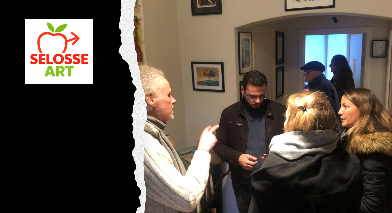 SELOSSE ART, artiste performeur basé à Bruxelles, engage une conversation avec plusieurs visiteurs dans une galerie d'art contemporain aux murs beiges ornés de cadres noirs contenant des dessins et reproductions.