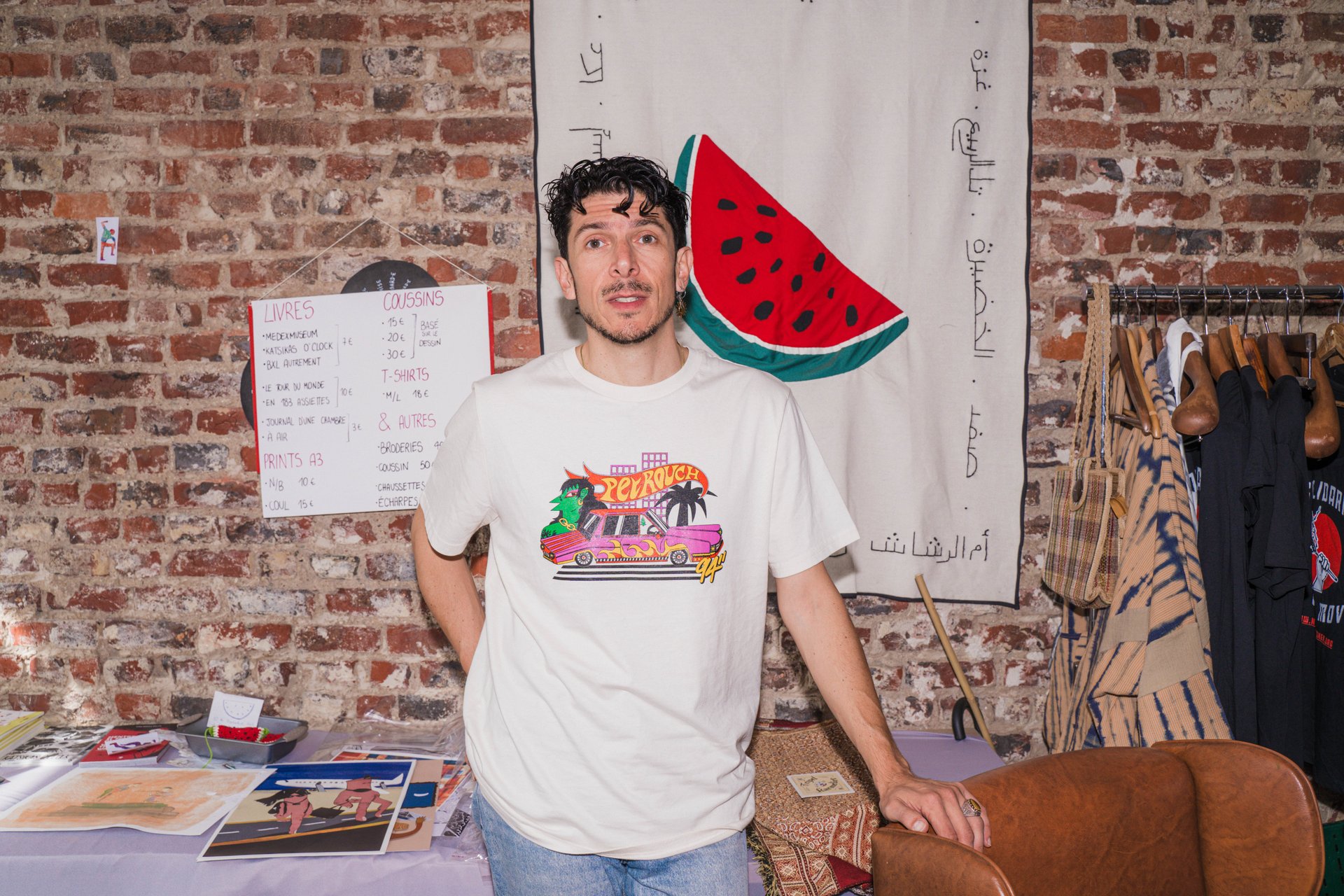 Portrait souriant de Daniele Manno (Maninelkaos) devant une pastèque en tissu et des bannières brodées. Artiste visuel, illustrateur et médiateur culturel italien installé à Bruxelles, Maninelkaos brode des foules fragiles autour de l'identité hybride, de l'exil et des migrations ; il présente « Fragile Humanity ». À découvrir à la Salle Dublin (étape n°48), 13 rue de Dublin, le vendredi 6 novembre de 18h à 22h, puis le samedi 7 et le dimanche 8 de 11h à 18h, pendant le Parcours d'Artistes d'Ixelles 2026.

Crédit photo - Gabrielle Liefooghe pour le Parcours d'Artistes d'Ixelles 2026 @googoo.eyes__ @ici_vaisseau_mere

Crédits & Liens :
Instagram : https://www.instagram.com/maninelkaos/
Fiche de l'événement (Dropmuse) : https://dropmuse.art/evenement/parcours-dartistes-dixelles-2026-ateliers-ouverts-creation-locale-ixelles-ixelles-bruxelles
Organisation : Vaisseau Mère — https://www.instagram.com/ici_vaisseau_mere/
Photographe Gabrielle Liefooghe : https://www.gabrielleliefooghe.com/ — https://www.instagram.com/googoo.eyes__/

Kult Ixelles sur DROPMUSE :
https://dropmuse.art/acteur-culturel/kult-ixelles-institution-residence-ixelles