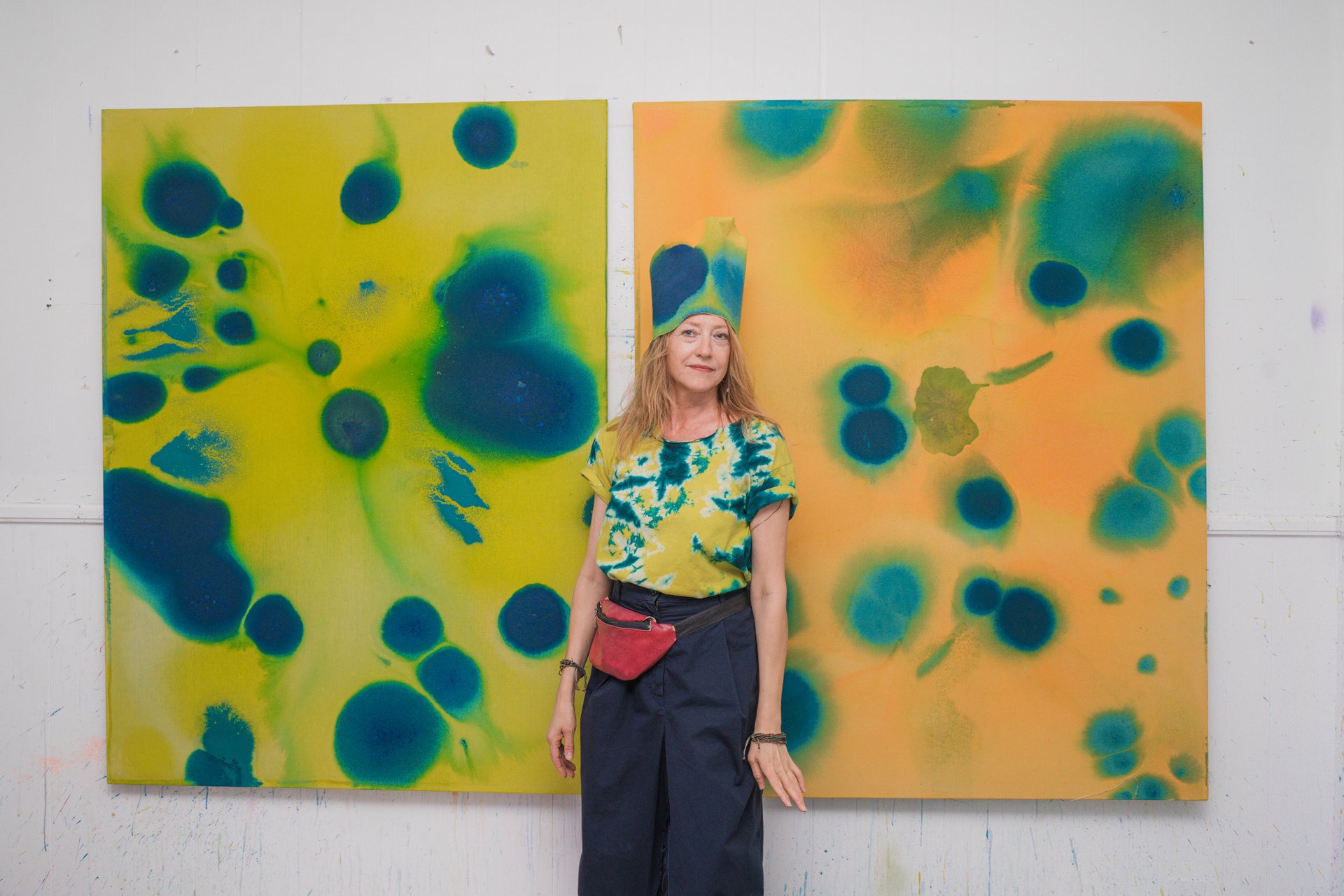 Portrait d'Ela Stasiuk devant deux grandes peintures aux taches bleues sur fond jaune et orange. Née à Białystok, formée à la tapisserie puis diplômée en peinture monumentale à l'Académie royale des Beaux-Arts de Bruxelles, Ela Stasiuk peint, entre abstraction et figuration, l'intangible, le rêve et le secret. À découvrir à UR Square (étape n°16), 227 avenue de la Couronne, le vendredi 6 novembre de 18h à 22h, puis le samedi 7 et le dimanche 8 de 11h à 18h, pendant le Parcours d'Artistes d'Ixelles 2026.

Crédit photo - Gabrielle Liefooghe pour le Parcours d'Artistes d'Ixelles 2026 @googoo.eyes__ @ici_vaisseau_mere

Crédits & Liens :
Instagram : https://www.instagram.com/ela_stasiuk/
Fiche de l'événement (Dropmuse) : https://dropmuse.art/evenement/parcours-dartistes-dixelles-2026-ateliers-ouverts-creation-locale-ixelles-ixelles-bruxelles
Organisation : Vaisseau Mère — https://www.instagram.com/ici_vaisseau_mere/
Photographe Gabrielle Liefooghe : https://www.gabrielleliefooghe.com/ — https://www.instagram.com/googoo.eyes__/

Kult Ixelles sur DROPMUSE :
https://dropmuse.art/acteur-culturel/kult-ixelles-institution-residence-ixelles