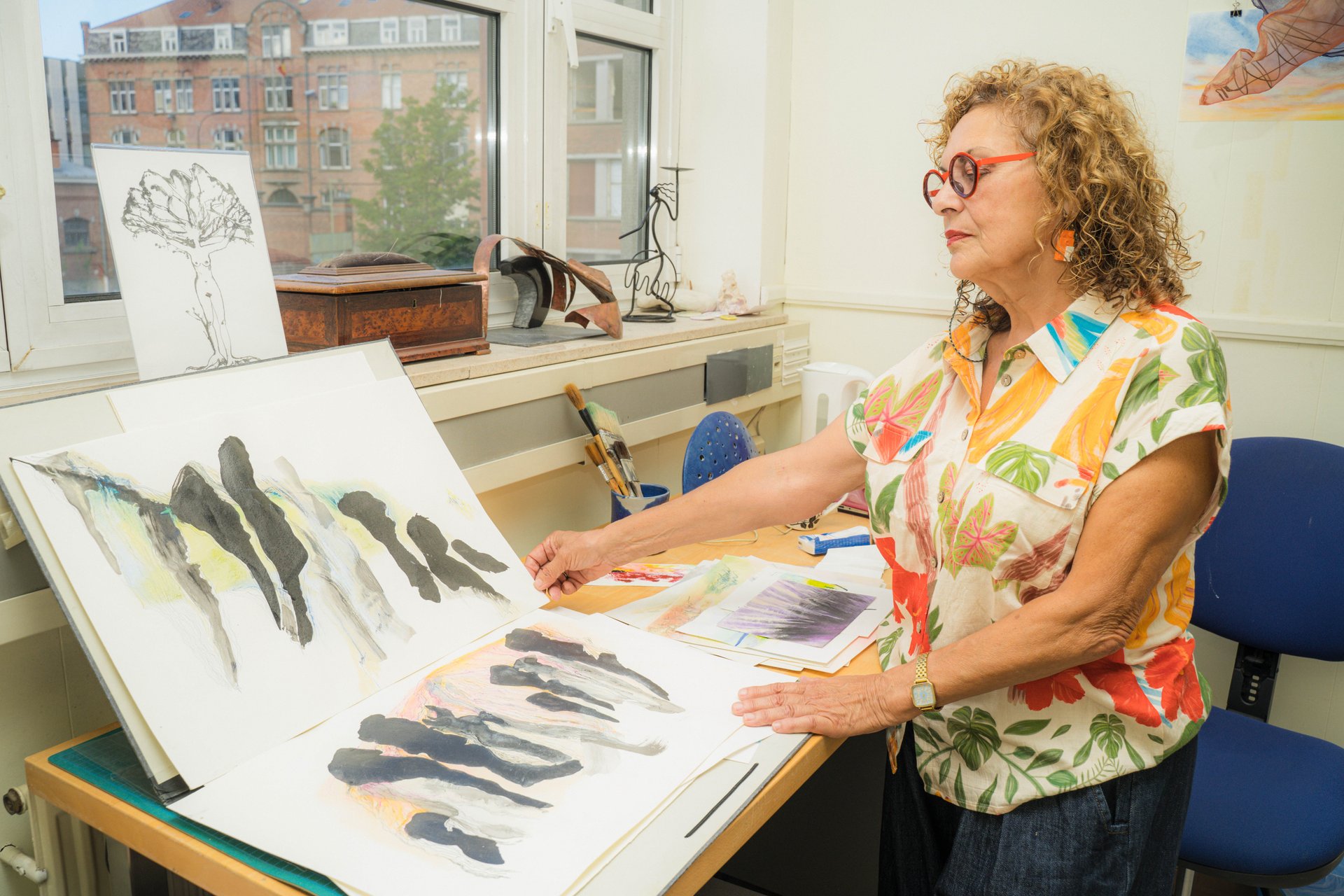 À sa table de travail, Maryvonne Prévot dévoile des dessins à l'encre noire et des aquarelles. Artiste pluridisciplinaire, entre dessin, peinture, céramique, poésie et clown, Maryvonne Prévot présente « Parcours », une installation de plaques de porcelaine décorées à l'encre. À découvrir à UR Square (étape n°16), 227 avenue de la Couronne, le vendredi 6 novembre de 18h à 22h, puis le samedi 7 et le dimanche 8 de 11h à 18h, pendant le Parcours d'Artistes d'Ixelles 2026.

Crédit photo - Gabrielle Liefooghe pour le Parcours d'Artistes d'Ixelles 2026 @googoo.eyes__ @ici_vaisseau_mere

Crédits & Liens :
Instagram : https://www.instagram.com/maryvonneprevot/
Fiche de l'événement (Dropmuse) : https://dropmuse.art/evenement/parcours-dartistes-dixelles-2026-ateliers-ouverts-creation-locale-ixelles-ixelles-bruxelles
Organisation : Vaisseau Mère — https://www.instagram.com/ici_vaisseau_mere/
Photographe Gabrielle Liefooghe : https://www.gabrielleliefooghe.com/ — https://www.instagram.com/googoo.eyes__/

Kult Ixelles sur DROPMUSE :
https://dropmuse.art/acteur-culturel/kult-ixelles-institution-residence-ixelles