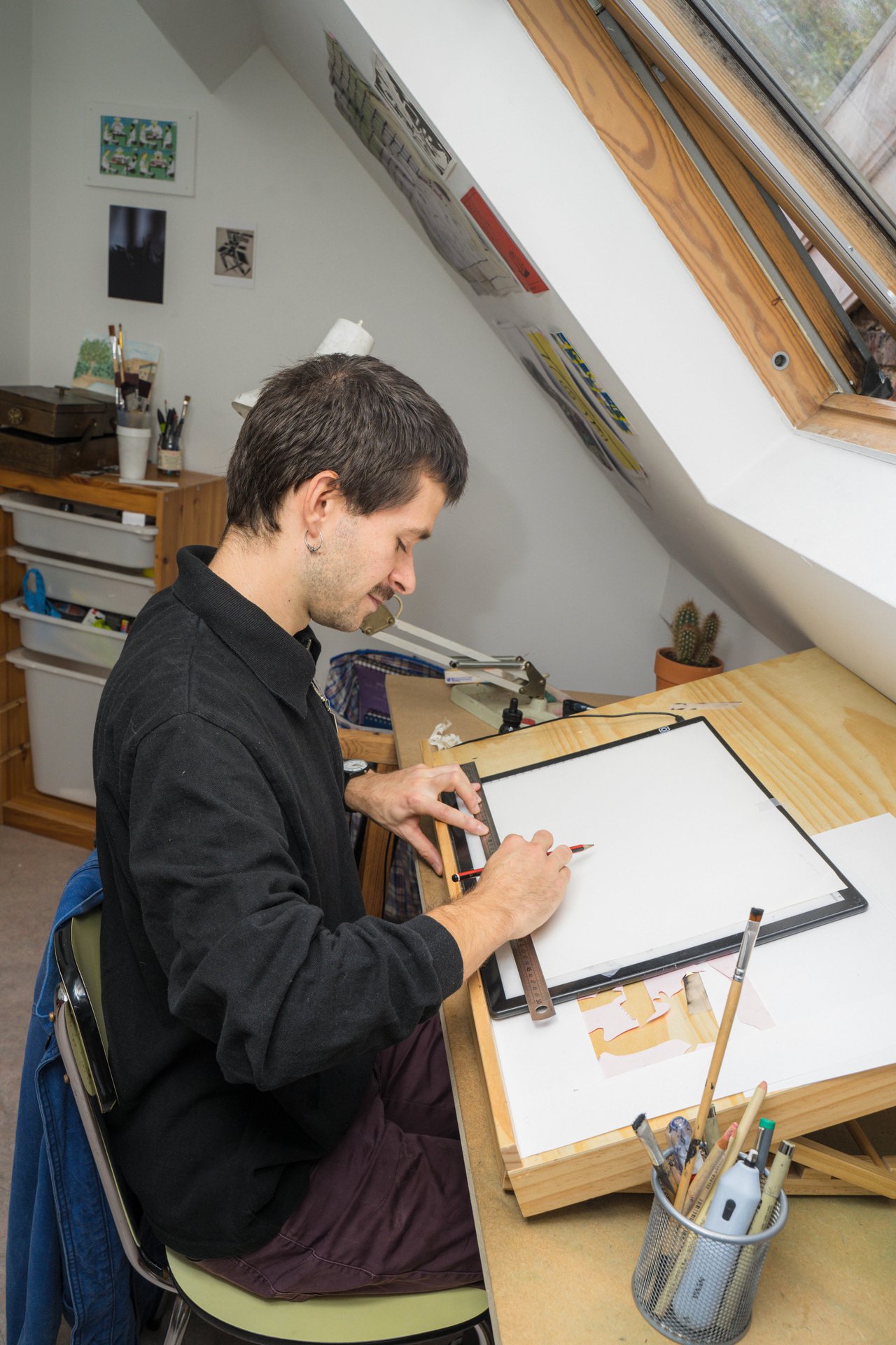 Sous la fenêtre de toit, le dessinateur Simon Boillat travaille sur une table lumineuse. Dessinateur de bande dessinée et illustrateur pour la presse, diplômé de Saint-Luc et de La Cambre, Simon Boillat fait partie de l'Atelier Serpentin, coorganisateur de l'exposition du 202 rue Gray. À découvrir à l'Atelier 202 (étape n°24), 202 rue Gray, le vendredi 6 novembre de 18h à 22h, puis le samedi 7 et le dimanche 8 de 11h à 18h, pendant le Parcours d'Artistes d'Ixelles 2026.

Crédit photo - Gabrielle Liefooghe pour le Parcours d'Artistes d'Ixelles 2026 @googoo.eyes__ @ici_vaisseau_mere

Crédits & Liens :
Instagram : https://www.instagram.com/6monboi2lat/
Fiche de l'événement (Dropmuse) : https://dropmuse.art/evenement/parcours-dartistes-dixelles-2026-ateliers-ouverts-creation-locale-ixelles-ixelles-bruxelles
Organisation : Vaisseau Mère — https://www.instagram.com/ici_vaisseau_mere/
Photographe Gabrielle Liefooghe : https://www.gabrielleliefooghe.com/ — https://www.instagram.com/googoo.eyes__/

Kult Ixelles sur DROPMUSE :
https://dropmuse.art/acteur-culturel/kult-ixelles-institution-residence-ixelles