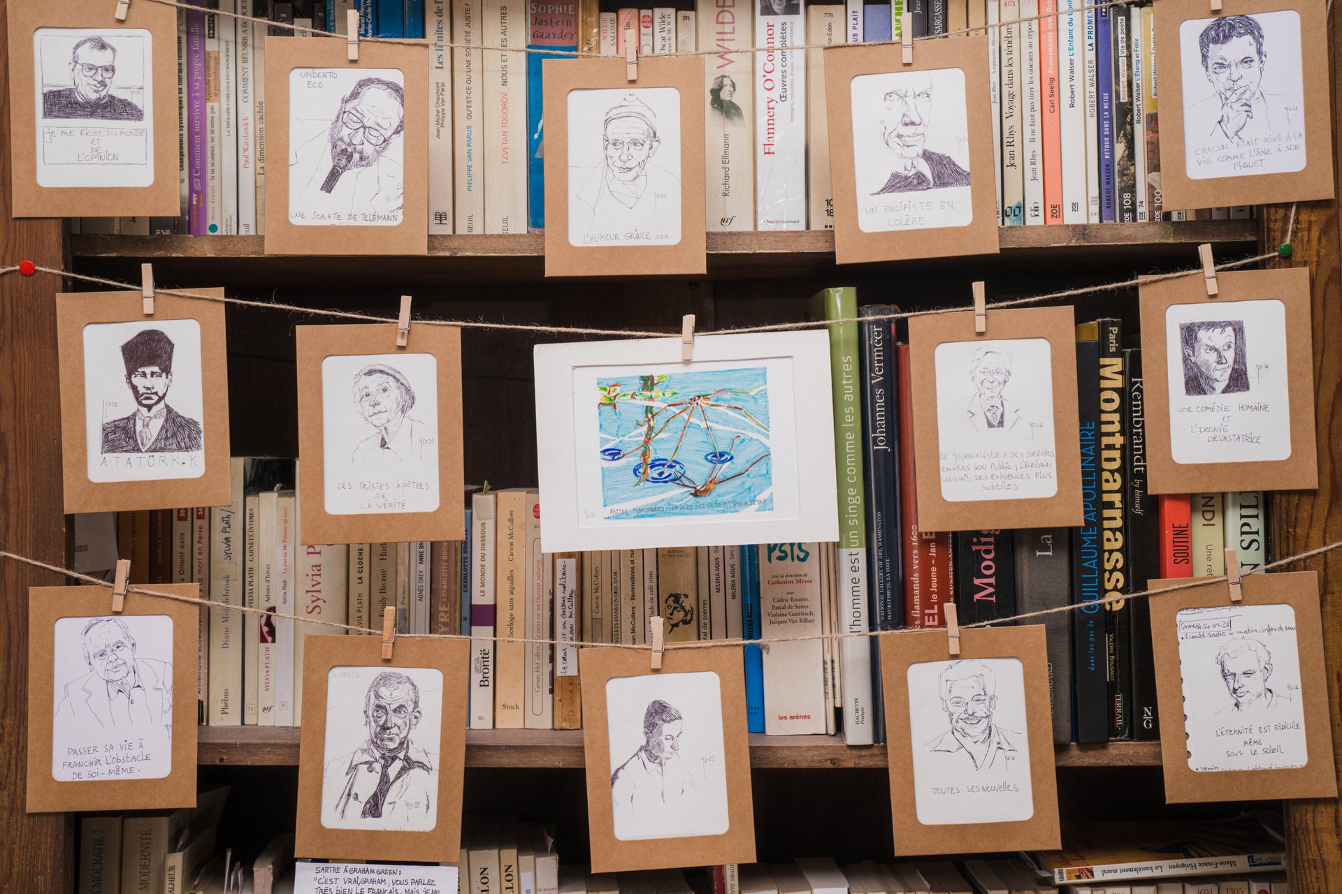 Les mini-portraits au bic d'Yves Delbar, suspendus par des pinces à linge devant une bibliothèque. Nouvelliste et dessinateur, Yves Delbar expose 60 miniatures au feutre inspirées de haïkus et 150 mini-portraits au bic noir, au format 10 x 12 cm. À découvrir à l'étape n°43 du parcours, 23 rue Jules Bouillon (3e étage), le vendredi 6 novembre de 18h à 22h, puis le samedi 7 et le dimanche 8 de 11h à 18h, pendant le Parcours d'Artistes d'Ixelles 2026.

Crédit photo - Gabrielle Liefooghe pour le Parcours d'Artistes d'Ixelles 2026 @googoo.eyes__ @ici_vaisseau_mere

Crédits & Liens :
Fiche de l'événement (Dropmuse) : https://dropmuse.art/evenement/parcours-dartistes-dixelles-2026-ateliers-ouverts-creation-locale-ixelles-ixelles-bruxelles
Organisation : Vaisseau Mère — https://www.instagram.com/ici_vaisseau_mere/
Photographe Gabrielle Liefooghe : https://www.gabrielleliefooghe.com/ — https://www.instagram.com/googoo.eyes__/

Kult Ixelles sur DROPMUSE :
https://dropmuse.art/acteur-culturel/kult-ixelles-institution-residence-ixelles