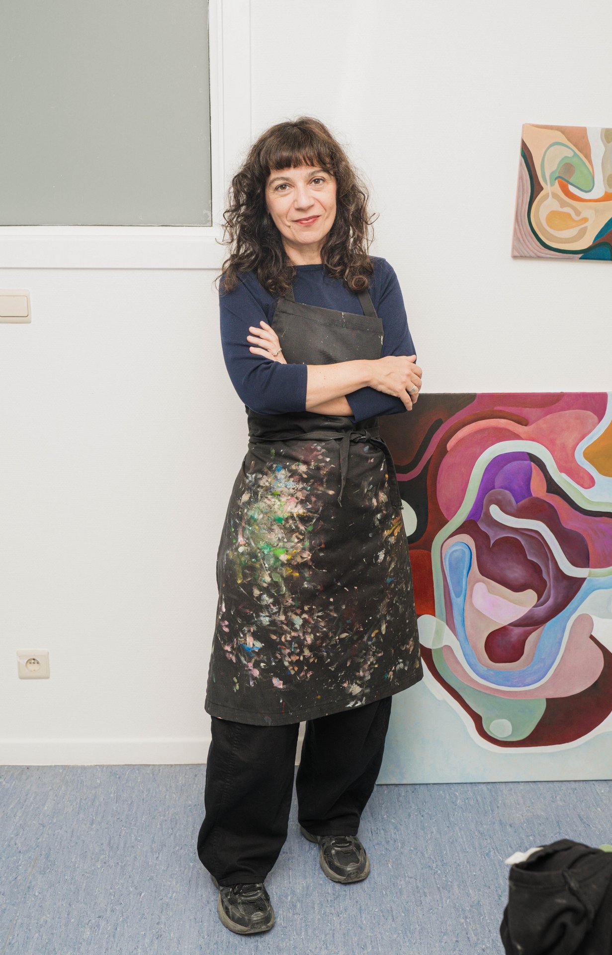 Portrait de l'artiste Zeta Tsermou en tablier de peintre, bras croisés, devant ses toiles aux formes organiques. Par la peinture, le dessin, la sculpture et la vidéo, Zeta Tsermou fragmente et recompose le corps pour explorer le désir et l'identité féminine. À découvrir à l'étape n°25 du parcours, 44 rue Dautzenberg, le vendredi 6 novembre de 18h à 22h, puis le samedi 7 et le dimanche 8 de 11h à 18h, pendant le Parcours d'Artistes d'Ixelles 2026.

Crédit photo - Gabrielle Liefooghe pour le Parcours d'Artistes d'Ixelles 2026 @googoo.eyes__ @ici_vaisseau_mere

Crédits & Liens :
Instagram : https://www.instagram.com/zetatsermou/
Site : https://zetatsermou.com
Fiche de l'événement (Dropmuse) : https://dropmuse.art/evenement/parcours-dartistes-dixelles-2026-ateliers-ouverts-creation-locale-ixelles-ixelles-bruxelles
Organisation : Vaisseau Mère — https://www.instagram.com/ici_vaisseau_mere/
Photographe Gabrielle Liefooghe : https://www.gabrielleliefooghe.com/ — https://www.instagram.com/googoo.eyes__/

Kult Ixelles sur DROPMUSE :
https://dropmuse.art/acteur-culturel/kult-ixelles-institution-residence-ixelles