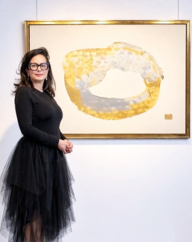 Saloua Sarhiri en robe noire et tulle positionnée près d'une de ses peintures abstraites aux teintes dorées et blanches encadrée, dans une galerie bruxelloise. Entre ombre et lumière, là où l’art parle sans mots.

#instamood #gold #black #inspiration