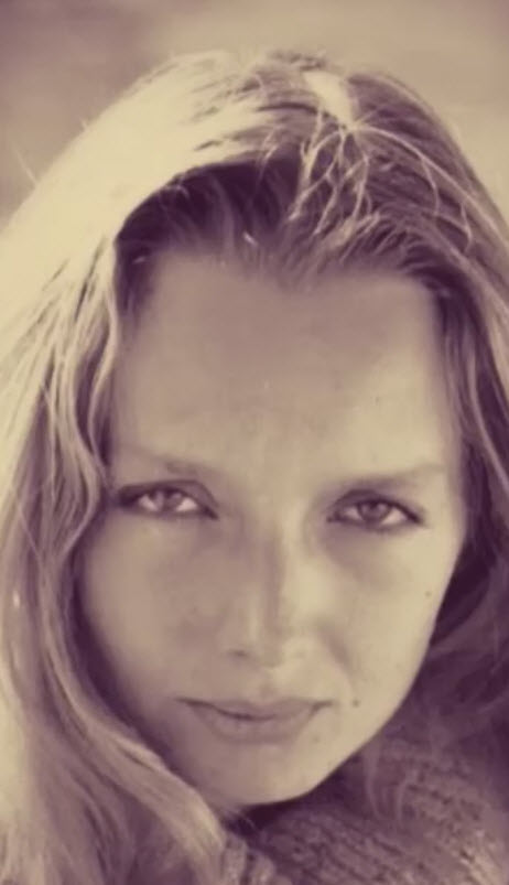 Photographie en noir et blanc de Oléna Rabitcheva de face, regard dirigé vers l'appareil, cheveux longs encadrant un visage aux traits délicats, tonalité sépia intemporelle. Artiste Plasticienne belge.