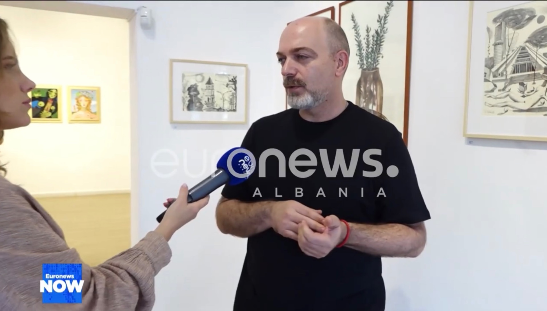 Dastid Miluka en interview dans une galerie, devant ses œuvres graphiques — Dastid Miluka