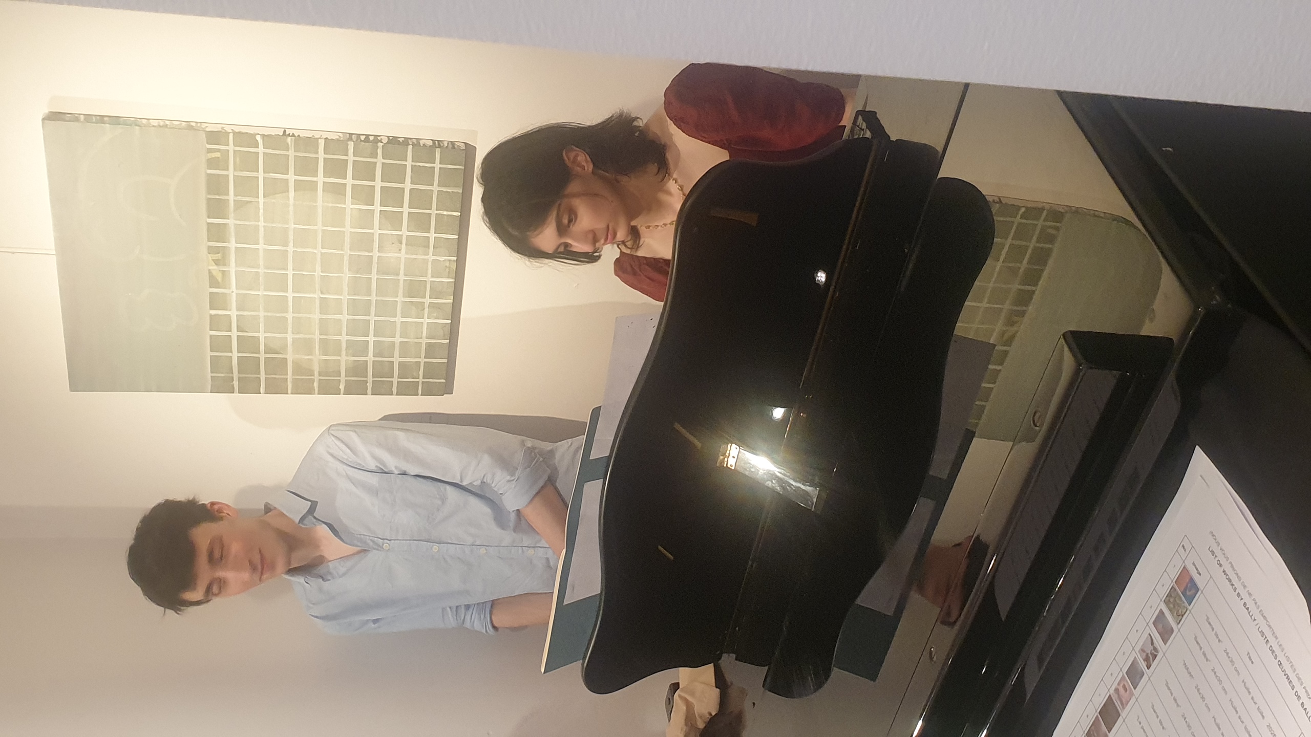 Deux membres du collectif Dropmuse.Art présentent une installation artistique numérique composée d'un écran noir interactif et de panneaux muraux, dans un espace blanc de la galerie artbase à bruxelles.